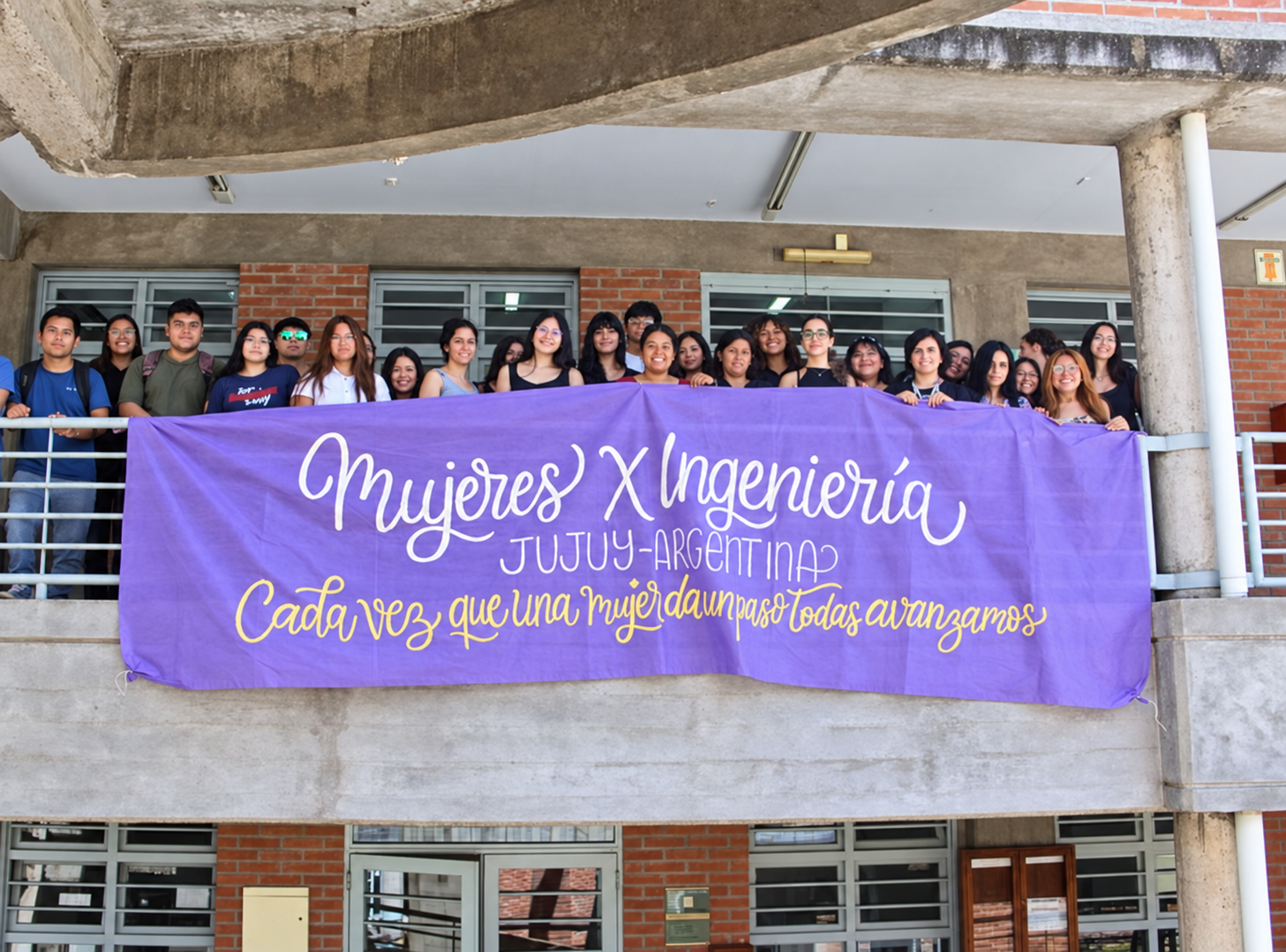 Integrantes de Mujeres x Ingeniería con su bandera violeta en la Facultad de Ingeniería de la UNJu